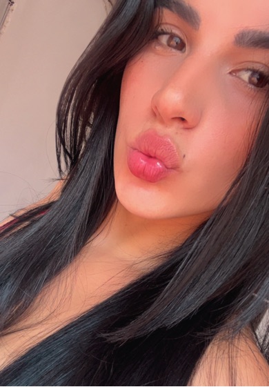 Woman with long black hair blowing a kiss at the camera